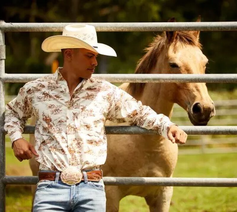 man in ariat shirt standing in front of a horse